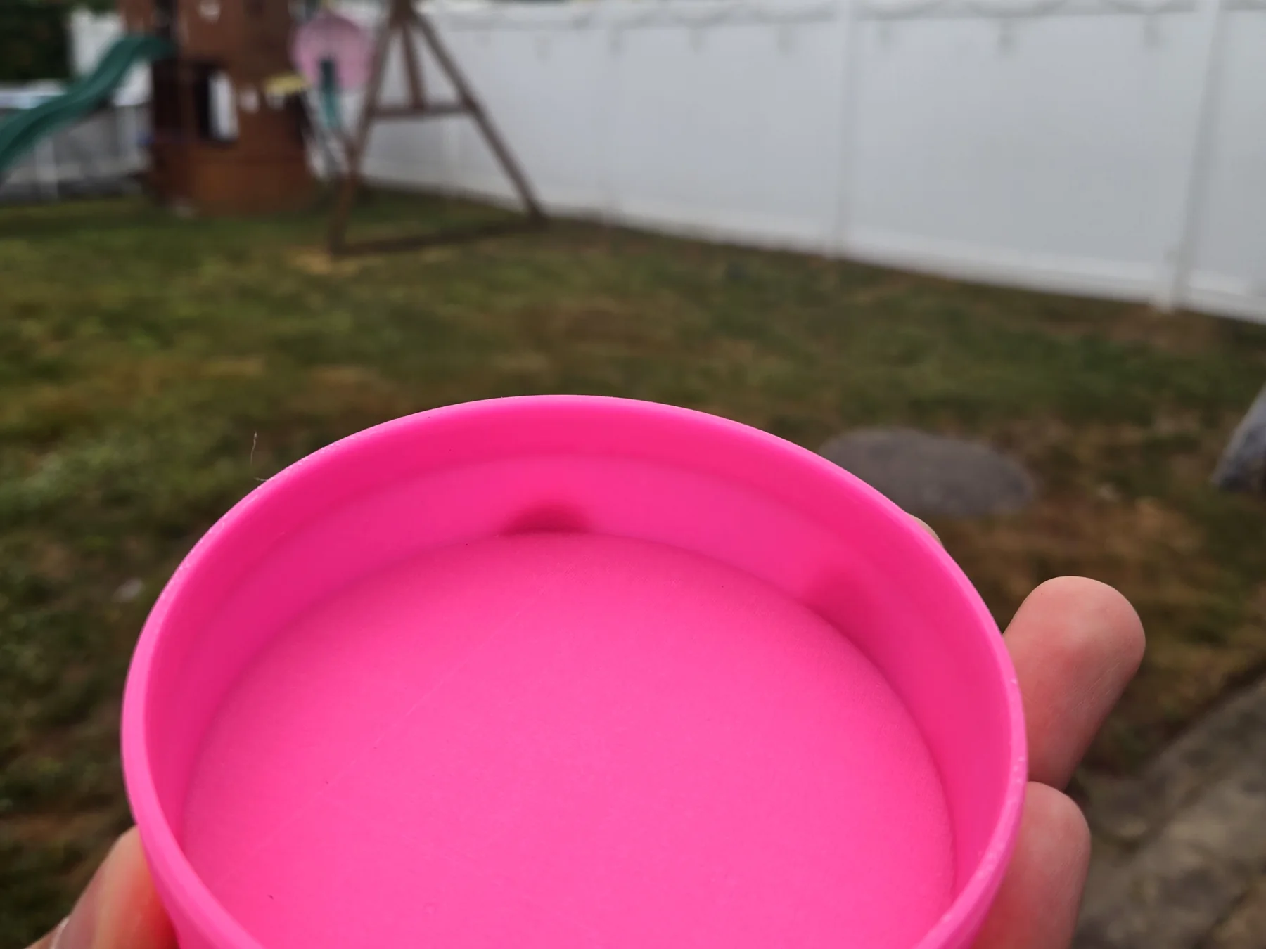 A pink 3D printed container held open in one hand, outdoors