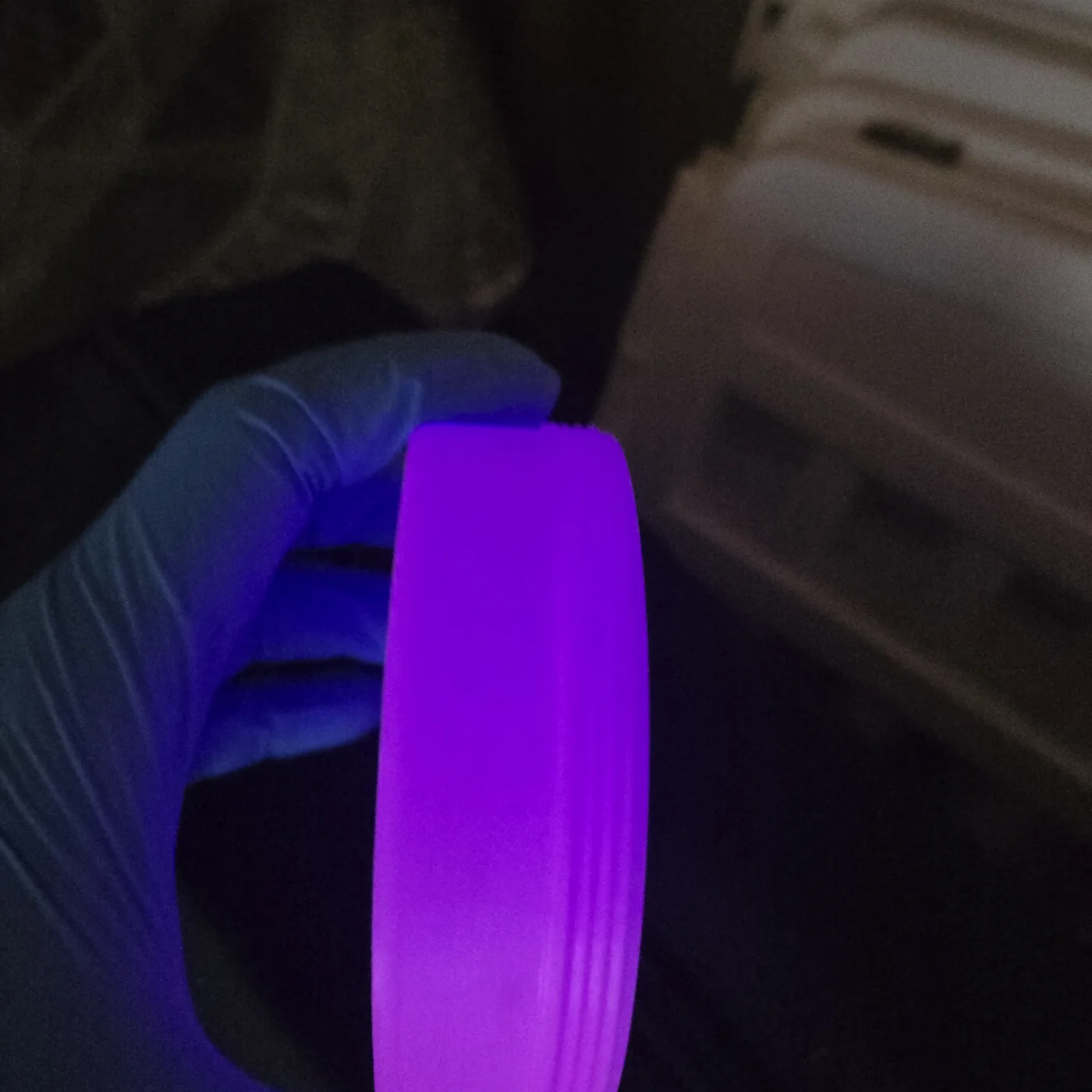 The same container glowing violet under a blacklight