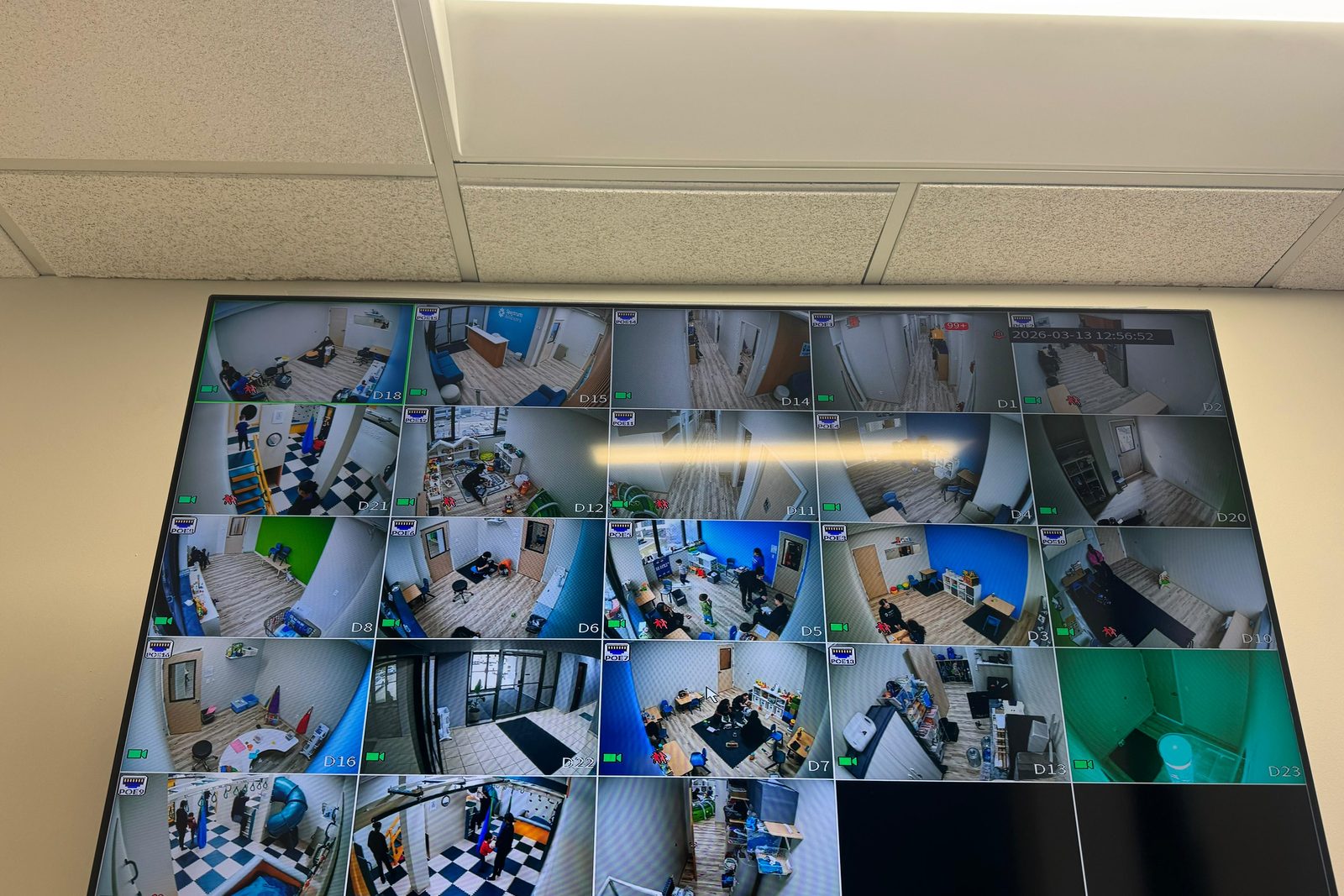 Wall-mounted monitor showing 25 live camera channels in an office